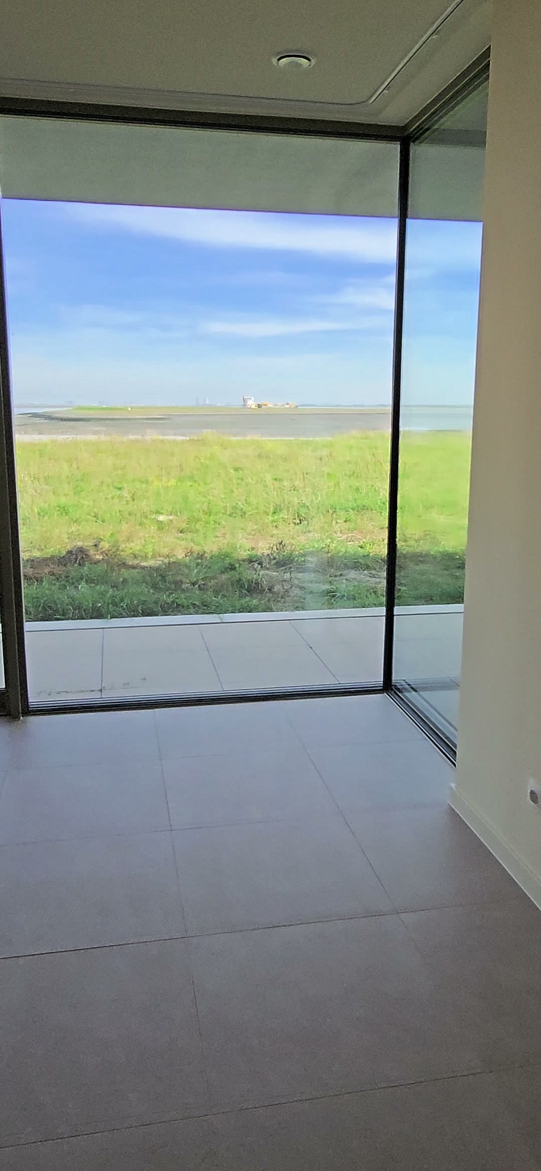 Leefruimte met glazen hoek en zicht op de Westerschelde